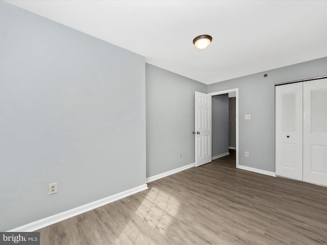 unfurnished bedroom featuring wood-type flooring and a closet