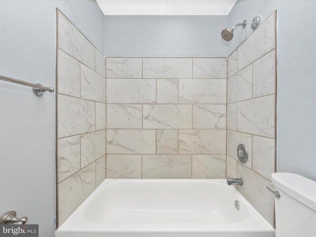 bathroom with tiled shower / bath combo and toilet