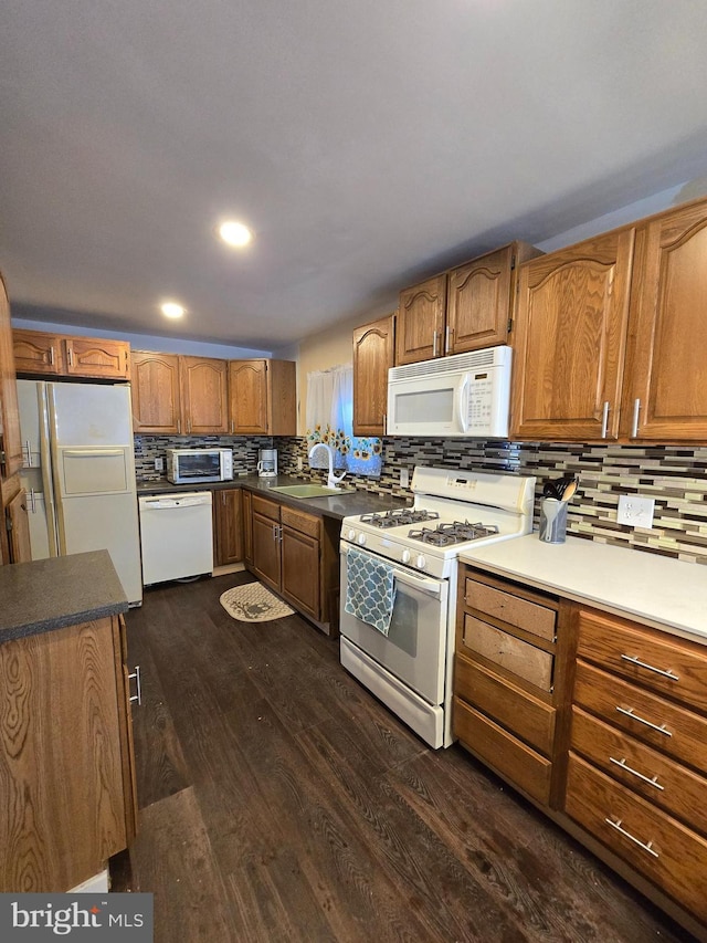 kitchen featuring white appliances, dark hardwood / wood-style floors, sink, and decorative backsplash