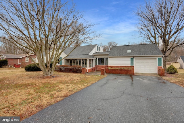 ranch-style house with brick siding, a shingled roof, a garage, driveway, and a front lawn