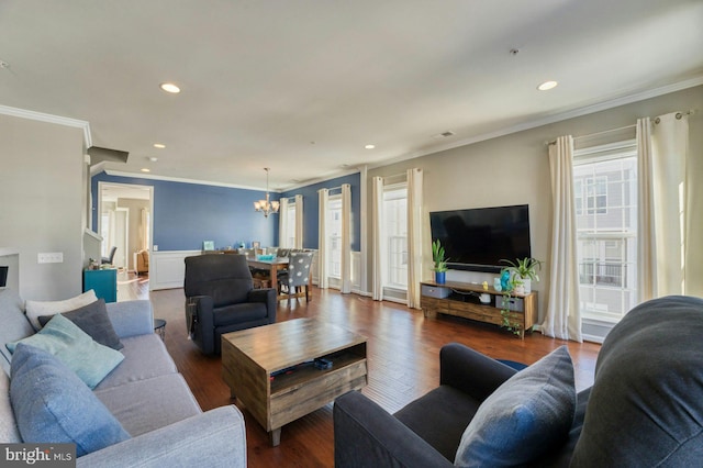 living room with an inviting chandelier, dark wood-type flooring, and ornamental molding