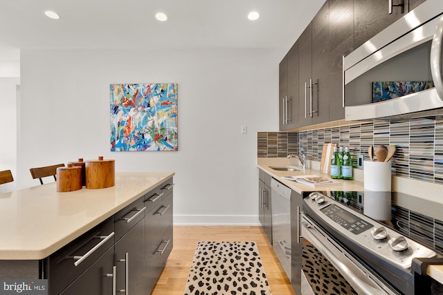 kitchen featuring a sink, decorative backsplash, stainless steel appliances, and light countertops