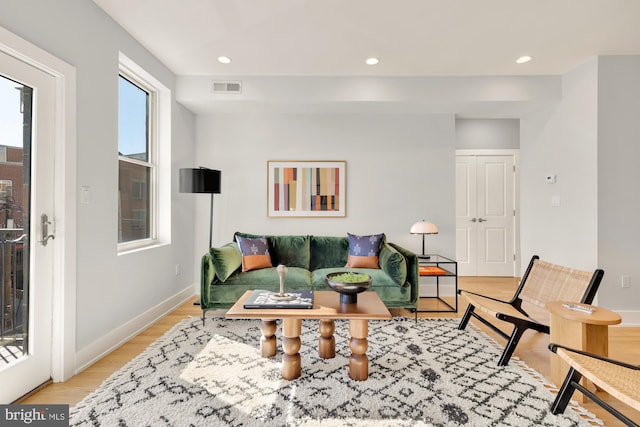 living room featuring light wood-style flooring, visible vents, baseboards, and recessed lighting