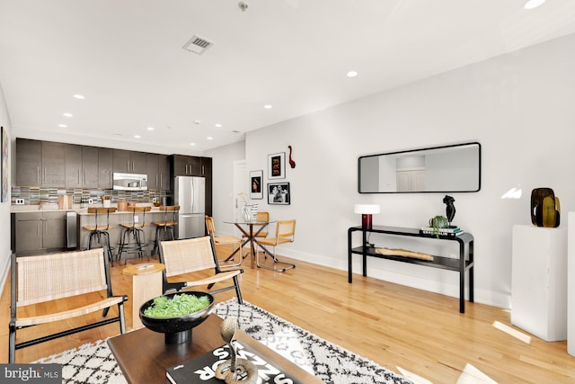 living area with light wood finished floors, baseboards, visible vents, and recessed lighting