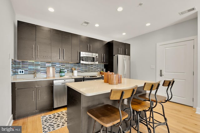 kitchen with a center island, light countertops, visible vents, appliances with stainless steel finishes, and a kitchen bar