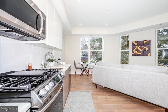 kitchen featuring white cabinetry, light wood-type flooring, plenty of natural light, and appliances with stainless steel finishes