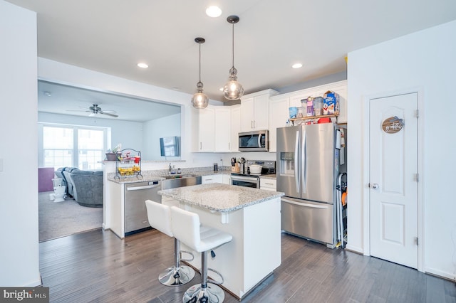 kitchen featuring pendant lighting, white cabinets, a kitchen breakfast bar, a center island, and stainless steel appliances