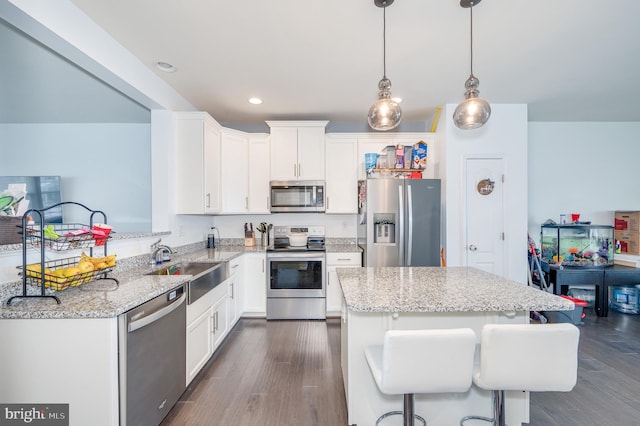 kitchen with stainless steel appliances, sink, white cabinets, and decorative light fixtures