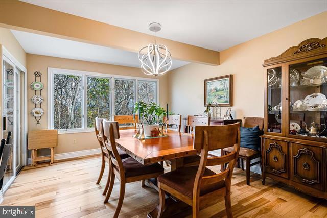 dining room with beamed ceiling, light hardwood / wood-style floors, and a notable chandelier