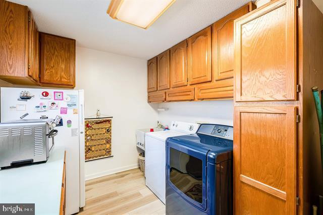 laundry area with cabinets, light wood-type flooring, and independent washer and dryer