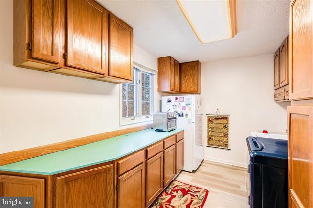 kitchen featuring white refrigerator, light hardwood / wood-style floors, and washer and dryer