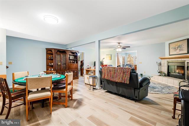 dining room with a tile fireplace, ceiling fan, and light hardwood / wood-style floors