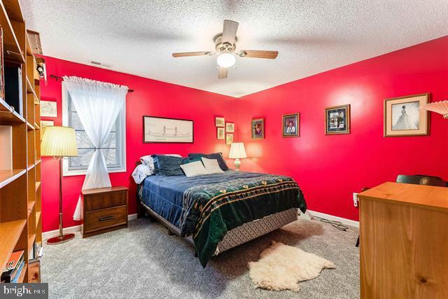 carpeted bedroom with ceiling fan and a textured ceiling