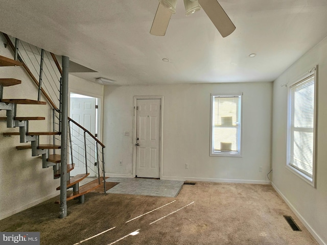 foyer entrance with light colored carpet and ceiling fan