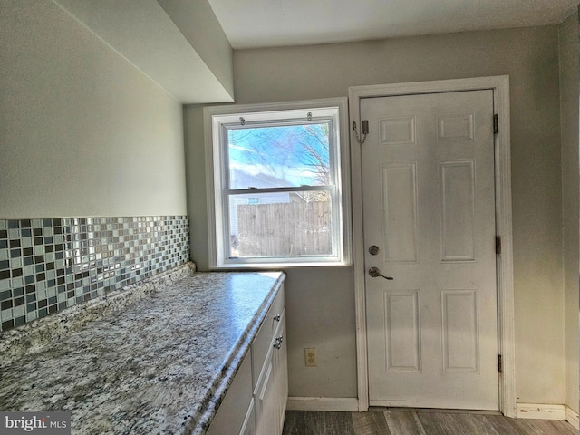 kitchen with light stone countertops, hardwood / wood-style floors, and decorative backsplash