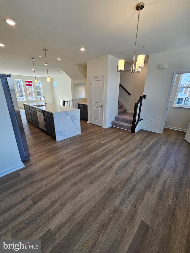 kitchen with pendant lighting, sink, dark wood-type flooring, and an island with sink