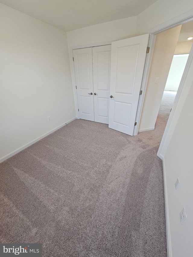 unfurnished bedroom featuring light carpet and a closet