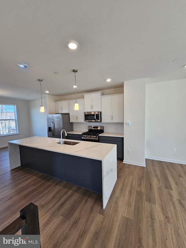 kitchen with sink, white cabinetry, hanging light fixtures, a kitchen island with sink, and stainless steel appliances