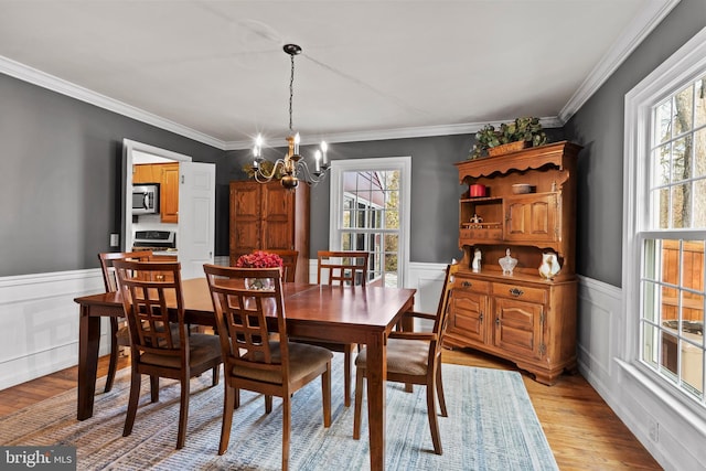 dining room featuring an inviting chandelier, a wealth of natural light, and light hardwood / wood-style flooring