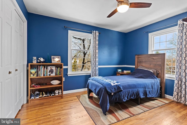 bedroom featuring ceiling fan, light wood-type flooring, and multiple windows