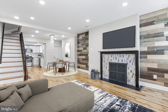 living room featuring sink, light hardwood / wood-style flooring, and wood walls