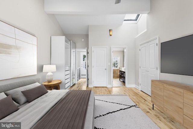 bedroom with high vaulted ceiling, beamed ceiling, and light hardwood / wood-style floors