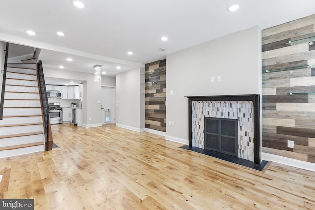 unfurnished living room featuring sink, wooden walls, and light hardwood / wood-style flooring