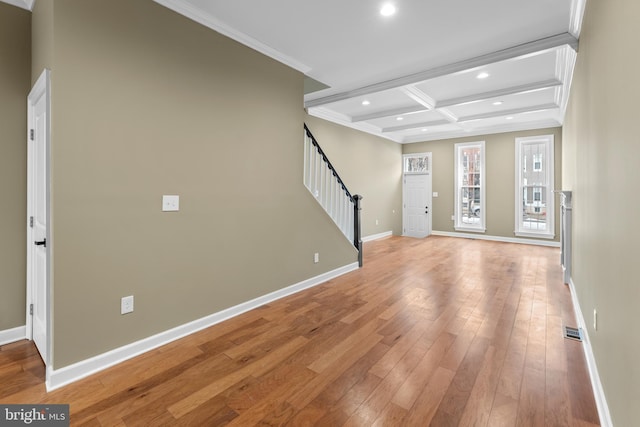 interior space with coffered ceiling, ornamental molding, beamed ceiling, and light wood-type flooring