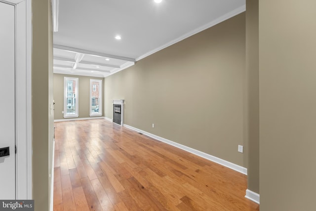 unfurnished living room featuring beamed ceiling, ornamental molding, coffered ceiling, and light wood-type flooring