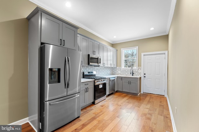 kitchen featuring backsplash, crown molding, gray cabinets, and appliances with stainless steel finishes