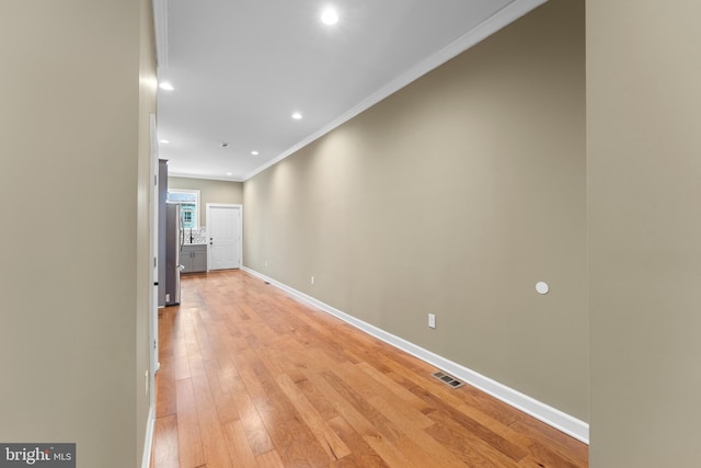 hallway with crown molding and light wood-type flooring