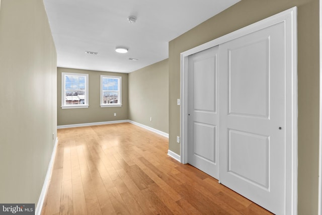 unfurnished bedroom with light wood-type flooring and a closet