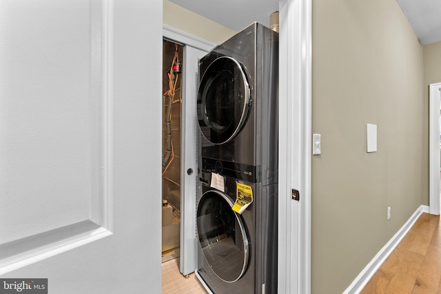 laundry area with hardwood / wood-style flooring and stacked washer / drying machine