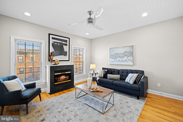 living room with ceiling fan, plenty of natural light, and light wood-type flooring