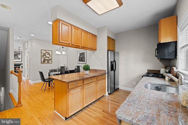 kitchen featuring sink, light hardwood / wood-style flooring, stainless steel fridge, light stone countertops, and kitchen peninsula