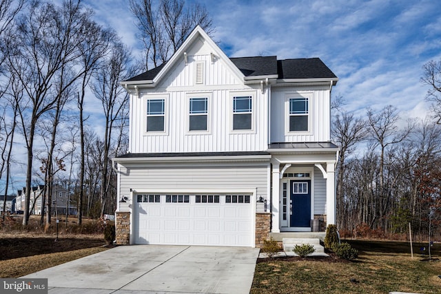 modern farmhouse with a garage, stone siding, driveway, and board and batten siding