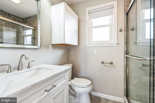 bathroom featuring toilet, vanity, and a shower with shower door