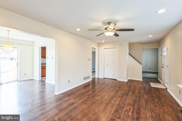 empty room with ceiling fan with notable chandelier and dark wood-type flooring