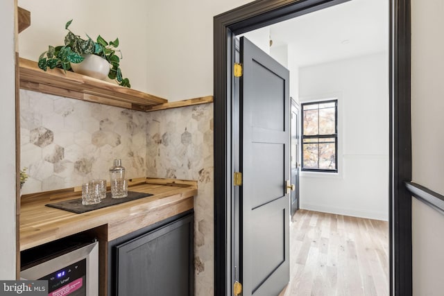 kitchen featuring light hardwood / wood-style floors, beverage cooler, wood counters, and decorative backsplash