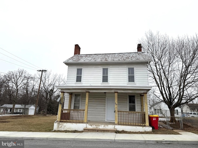 front facade featuring covered porch and a front yard