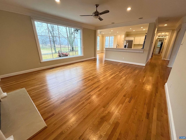 unfurnished living room with ceiling fan, ornamental molding, and light hardwood / wood-style flooring