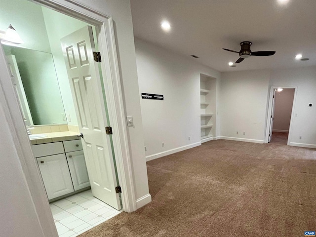 hallway featuring sink, light colored carpet, and built in features