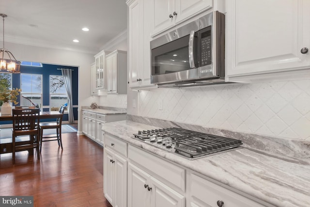 kitchen with pendant lighting, ornamental molding, white cabinets, and appliances with stainless steel finishes