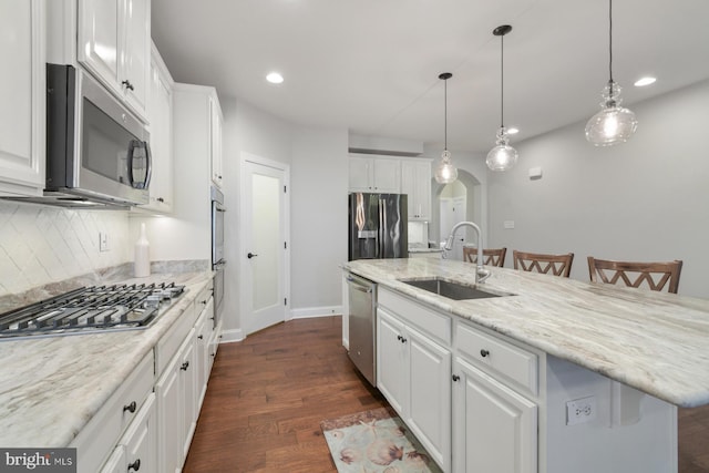 kitchen with appliances with stainless steel finishes, a breakfast bar, white cabinetry, sink, and a kitchen island with sink