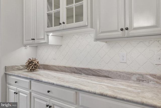 kitchen with white cabinetry, light stone counters, and decorative backsplash