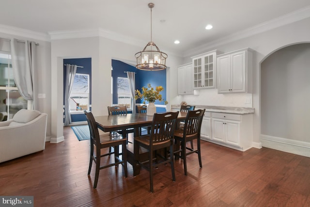 dining room with an inviting chandelier, ornamental molding, and dark hardwood / wood-style floors