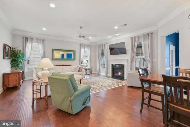 living room featuring crown molding, dark wood-type flooring, a wealth of natural light, and ceiling fan