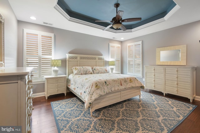 bedroom with a raised ceiling, ornamental molding, and dark wood-type flooring