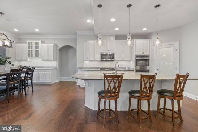 kitchen with decorative light fixtures, stainless steel appliances, and white cabinets