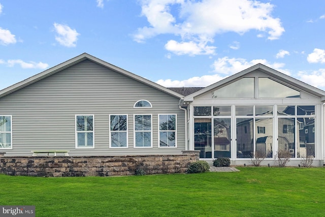 back of property with a sunroom and a lawn